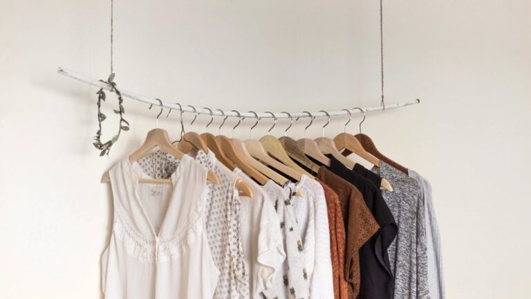Person browsing a rack of affordable secondhand clothes in a thrift store