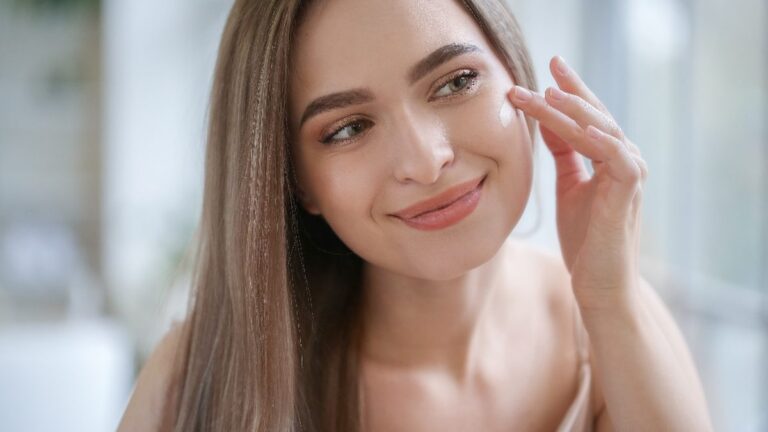Woman looking closely at her facial skin in a bathroom mirror to work out her skin type